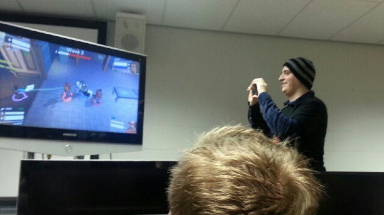 A picture of a couple of members from the team, watching the game being played on the TV.